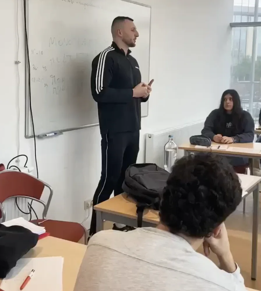 nutrition-et-sport Un intervenant debout devant un tableau blanc parle aux élèves dans une salle de classe.